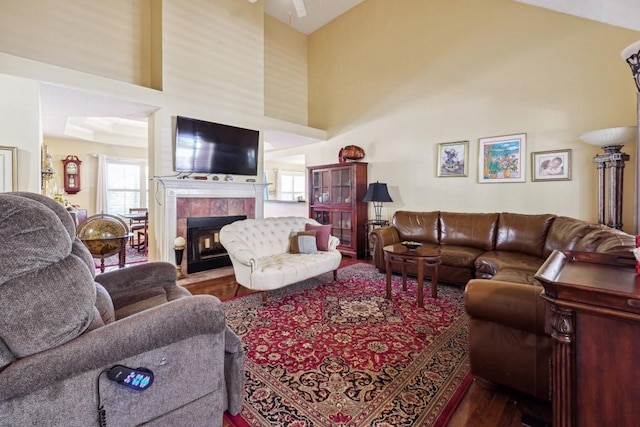 living room featuring hardwood / wood-style floors, high vaulted ceiling, and a tiled fireplace