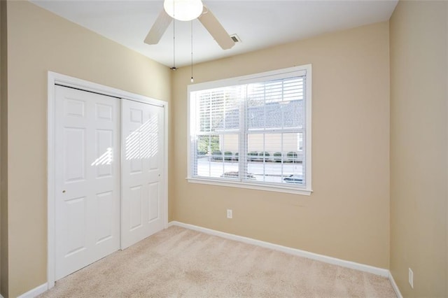 unfurnished bedroom with light carpet, a closet, and ceiling fan