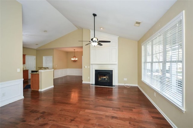 unfurnished living room featuring lofted ceiling, a fireplace, dark hardwood / wood-style flooring, and ceiling fan with notable chandelier