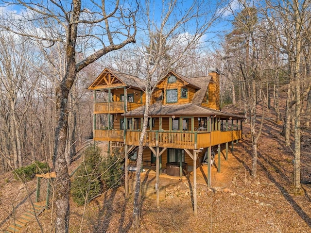 back of property with a chimney, a balcony, and a shingled roof