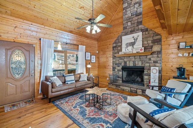 living room featuring a ceiling fan, wood finished floors, a fireplace, wood ceiling, and wood walls