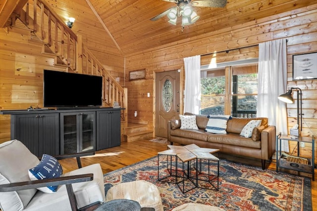 living room with wooden walls, wood ceiling, wood finished floors, high vaulted ceiling, and a ceiling fan