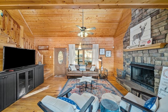 living area featuring wood walls, wood ceiling, light wood-type flooring, vaulted ceiling, and a fireplace