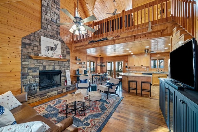 living area with wooden ceiling, wooden walls, a fireplace, and light wood finished floors