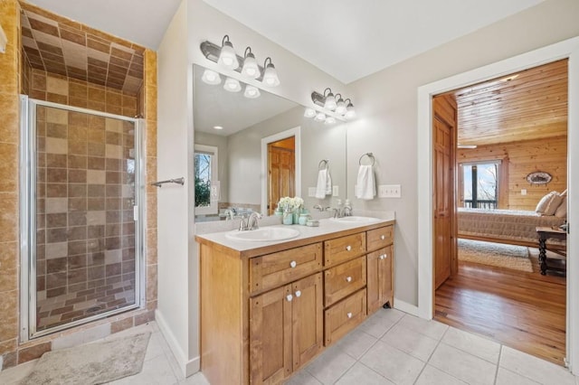 bathroom featuring tile patterned flooring, double vanity, a stall shower, ensuite bath, and a sink