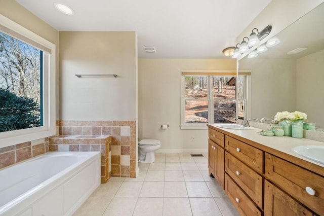 full bathroom featuring tile patterned flooring, visible vents, double vanity, a bath, and a sink