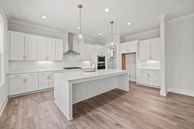 kitchen featuring stainless steel microwave, wall oven, white cabinets, a sink, and wall chimney range hood