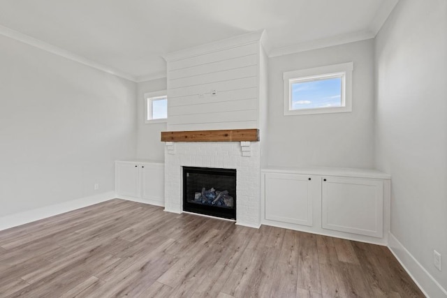 unfurnished living room with a brick fireplace, baseboards, crown molding, and light wood finished floors