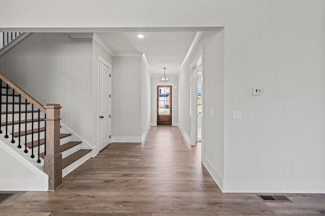 foyer entrance featuring stairs, baseboards, wood finished floors, and crown molding