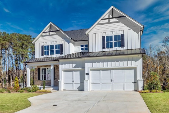 modern farmhouse style home with an attached garage, board and batten siding, a front yard, a standing seam roof, and driveway