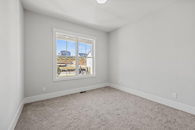 spare room featuring carpet, visible vents, and baseboards