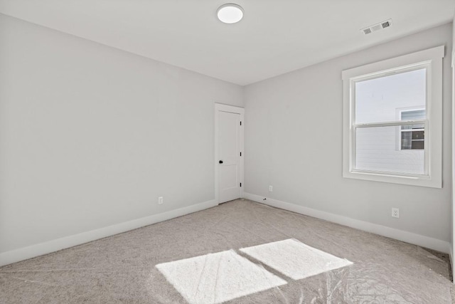 carpeted spare room with visible vents and baseboards