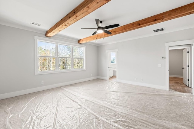 empty room featuring visible vents, attic access, beam ceiling, and baseboards