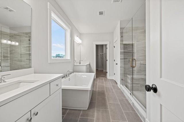 full bath with a stall shower, visible vents, and two vanities