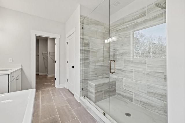 bathroom featuring a stall shower, a spacious closet, baseboards, and vanity