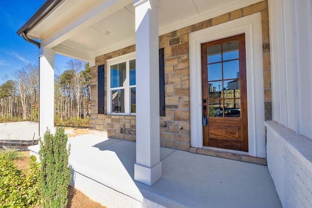 entrance to property featuring stone siding and a porch