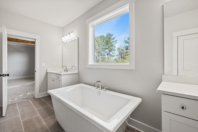 bathroom featuring a soaking tub, vanity, and baseboards