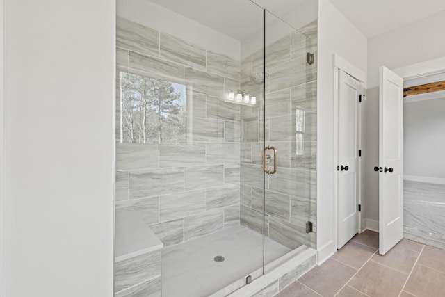 full bath featuring a stall shower, tile patterned floors, and baseboards