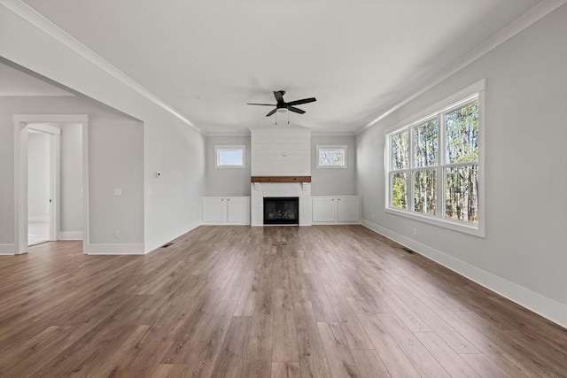 unfurnished living room featuring a fireplace, ornamental molding, a ceiling fan, wood finished floors, and baseboards