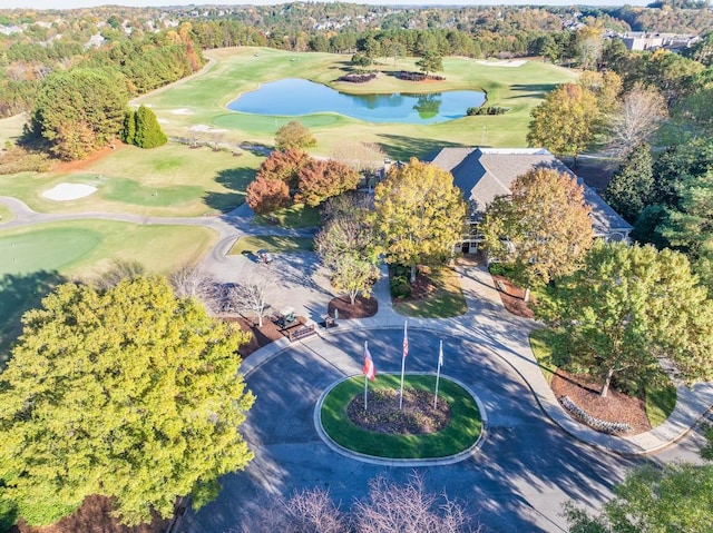 drone / aerial view featuring golf course view, a water view, and a view of trees