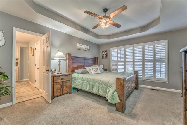 bedroom with visible vents, carpet flooring, baseboards, and a tray ceiling