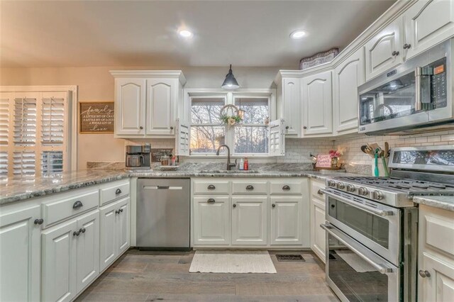 kitchen with decorative backsplash, white cabinets, stainless steel appliances, and a sink