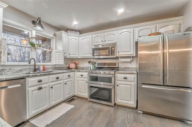 kitchen featuring a sink, decorative backsplash, white cabinetry, and stainless steel appliances