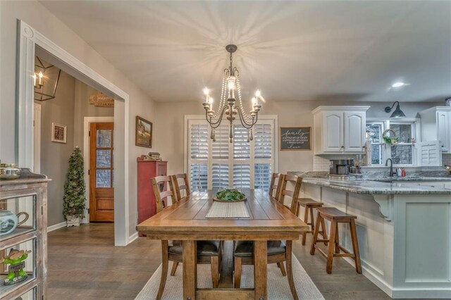 dining space featuring a chandelier, dark wood-type flooring, and baseboards