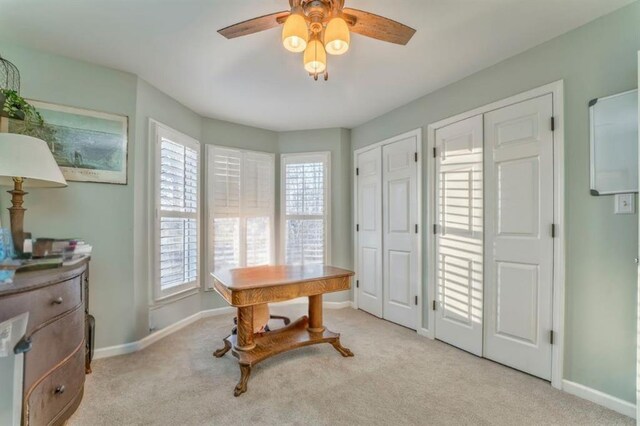 office space with carpet flooring, a ceiling fan, and baseboards