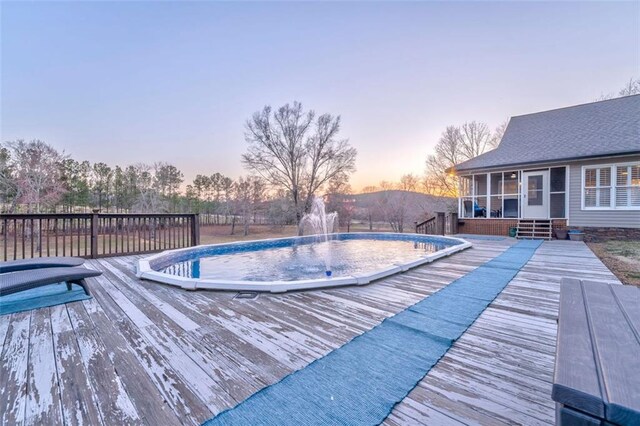 view of pool featuring a deck and a sunroom