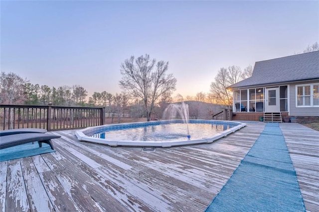 view of pool with a wooden deck and a sunroom