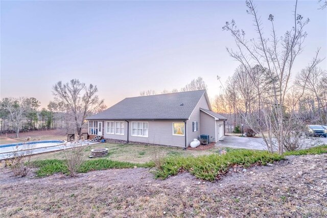 back of house featuring a pool, a fire pit, and a garage