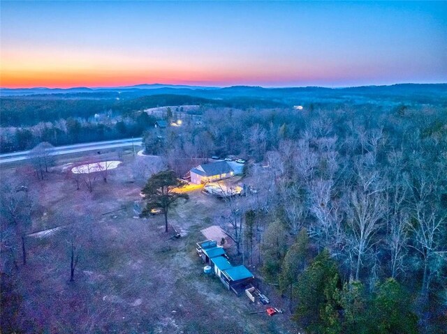 aerial view at dusk featuring a forest view and a mountain view