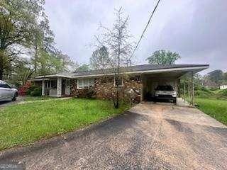 ranch-style home with driveway, a front lawn, and an attached carport