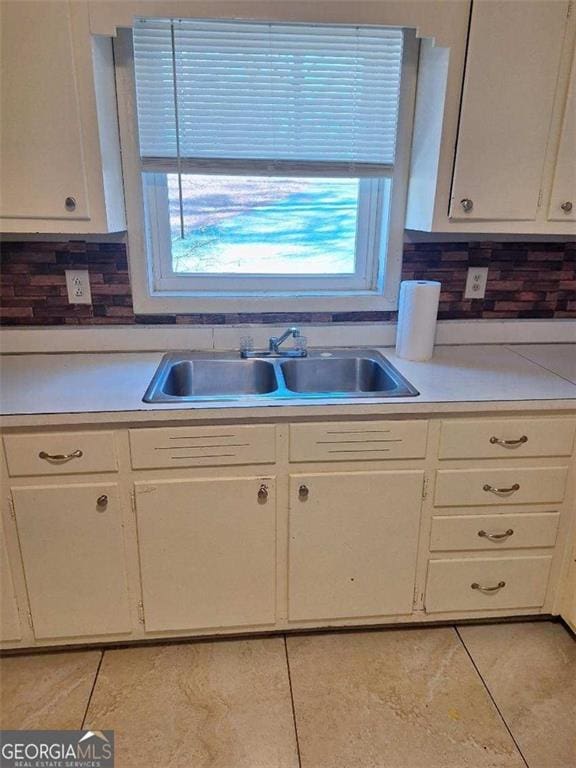 kitchen featuring light tile patterned floors, light countertops, a sink, and white cabinetry