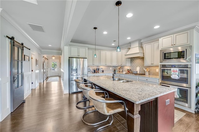 4578 Big Rock Ridge Trl, Gainesville, GA 30504 - kitchen with appliances with stainless steel finishes, custom exhaust hood, a barn door, ornamental molding, and light stone counters