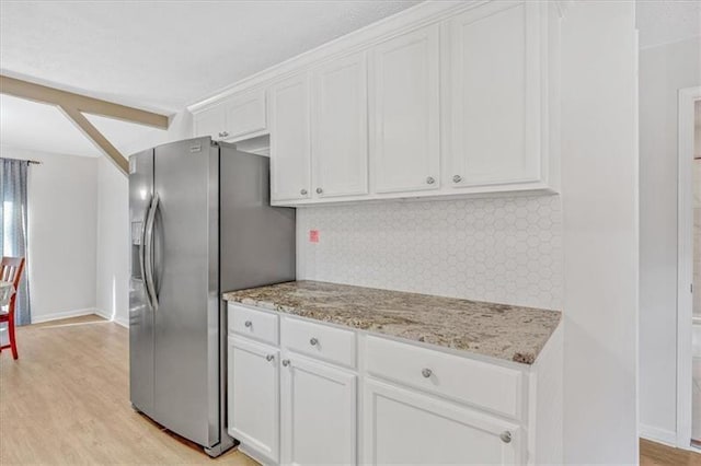 kitchen featuring light stone countertops, light wood finished floors, stainless steel fridge with ice dispenser, white cabinets, and tasteful backsplash