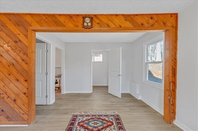 interior space featuring a healthy amount of sunlight, a textured ceiling, and light wood-style flooring