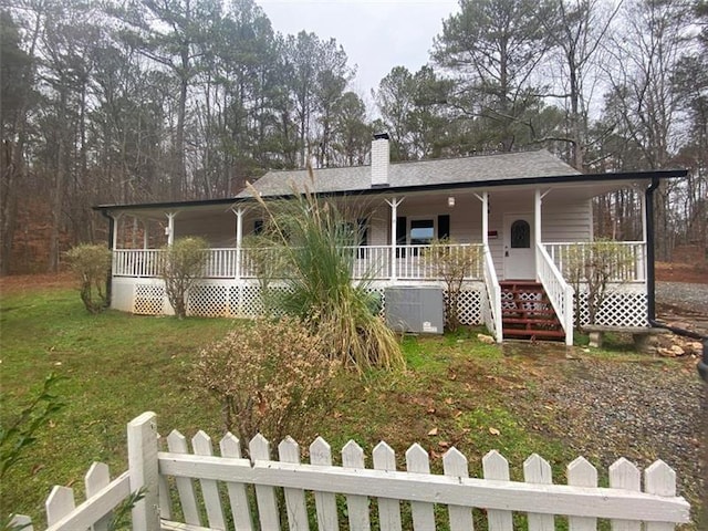 view of front of home with a front yard, fence, covered porch, and a chimney