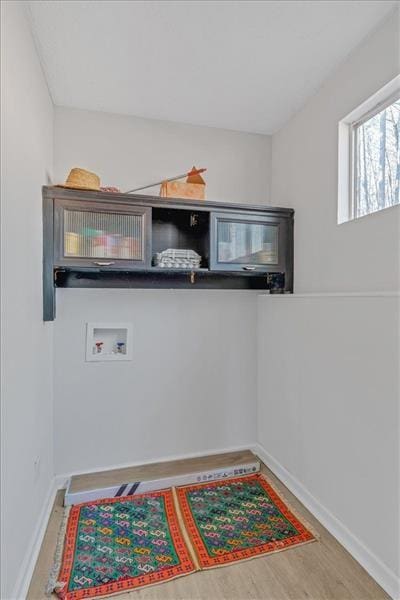 laundry area with baseboards, washer hookup, wood finished floors, and laundry area