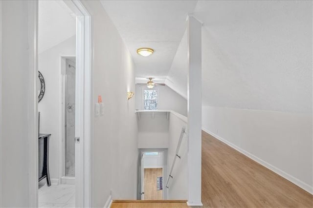 staircase with baseboards, wood finished floors, and vaulted ceiling