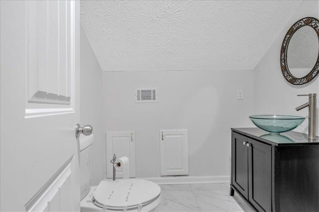 bathroom with baseboards, visible vents, lofted ceiling, a textured ceiling, and marble finish floor