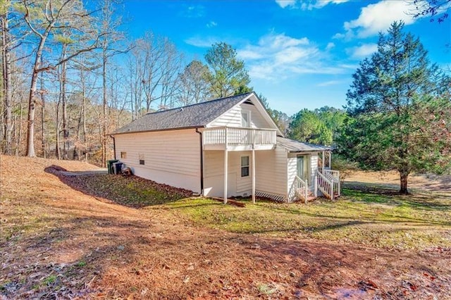 view of side of property featuring a balcony and a lawn