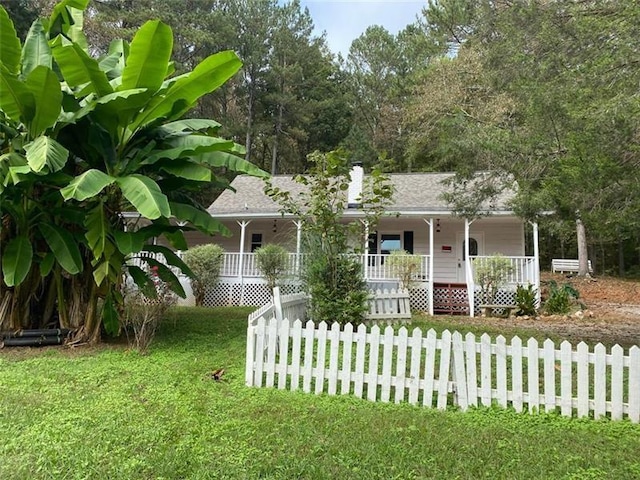 view of front of home with a fenced front yard, roof with shingles, covered porch, and a front lawn