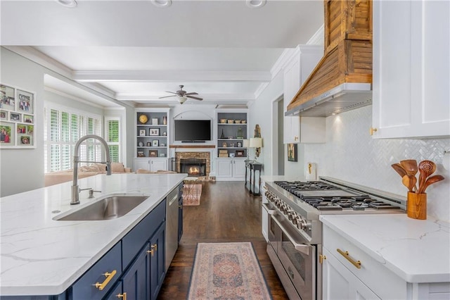 kitchen featuring stainless steel appliances, a sink, blue cabinetry, a ceiling fan, and white cabinets