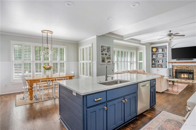 kitchen with a sink, blue cabinets, dishwasher, open floor plan, and crown molding