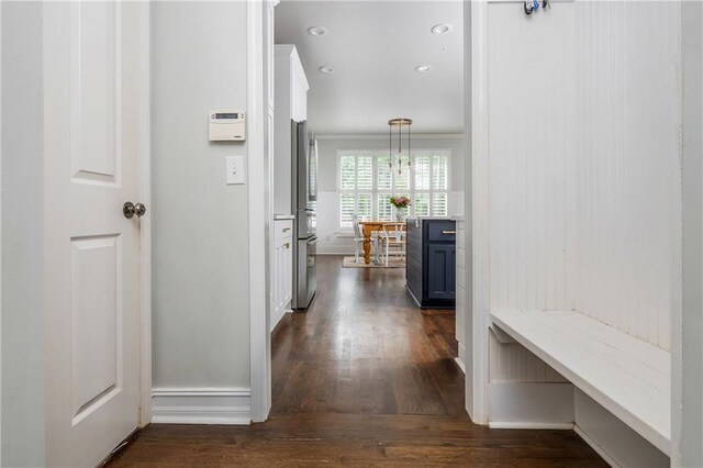 corridor featuring dark wood finished floors, baseboards, ornamental molding, and recessed lighting