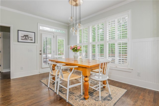 dining room with dark wood-style flooring, crown molding, healthy amount of natural light, wainscoting, and a decorative wall