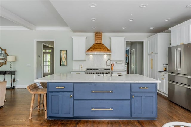 kitchen with freestanding refrigerator, custom exhaust hood, white cabinets, blue cabinetry, and ornamental molding