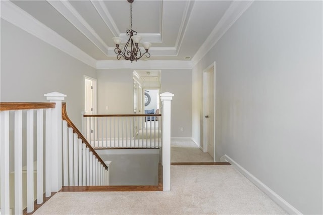 stairs with a chandelier, carpet flooring, crown molding, and a raised ceiling